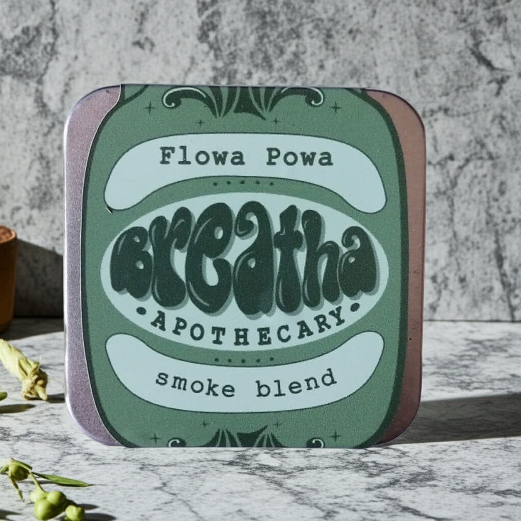 Tin labeled 'Flowa Powa Breatha Apothecary smoke blend' on a marble surface with a gray background.
